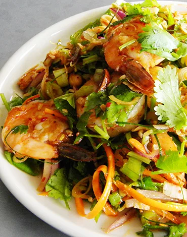 Traditional Thai larb salad with fresh herbs, vegetables, and shrimp