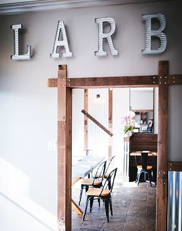 Interior of Larb Thai restaurant showing dining area with wooden tables and industrial decor
