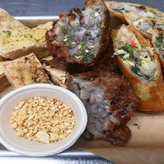 Fried tofu, spring rolls, fried meat patties, ground peanuts, and dipping sauce on a tray.