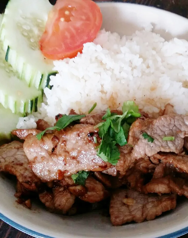 Grilled pork with jasmine rice, cucumber, and tomato garnish