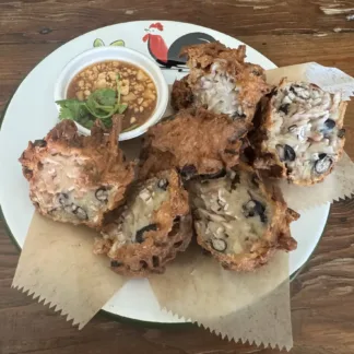 Deep fried taro balls on a plate, served with a garlic-chili sauce topped with crushed peanuts and cilantro.
