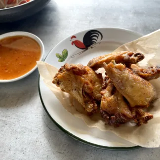 Crispy fried chicken wings on a plate, with a side of sweet garlic sauce
