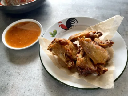 Crispy fried chicken wings on a plate, with a side of sweet garlic sauce